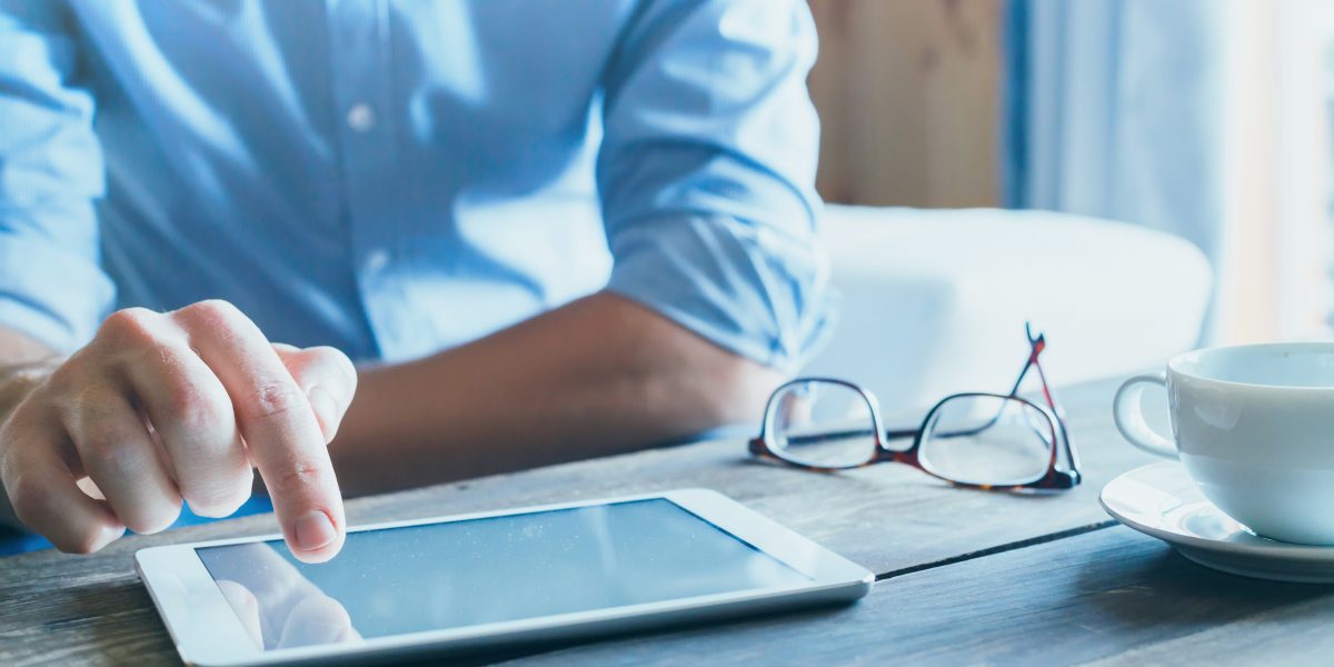 Un homme qui consulte sa tablette lors d'une pause café