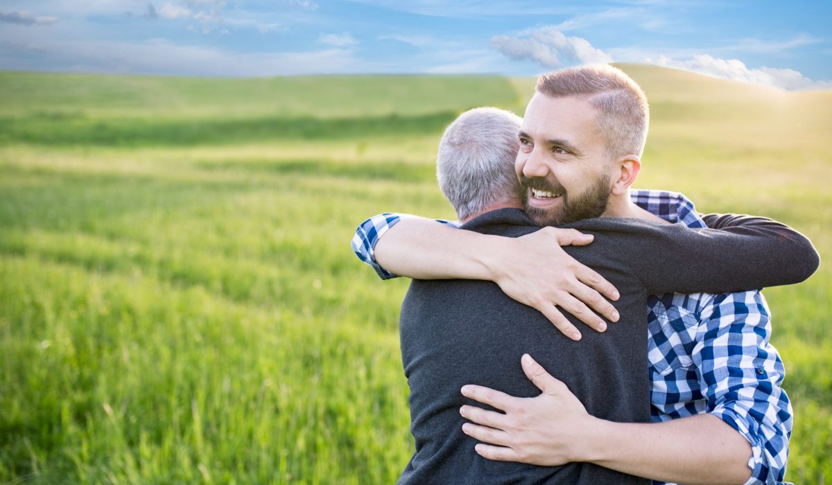 Un homme et son père dans les bras l'un de l'autre au milieu d'une plaine