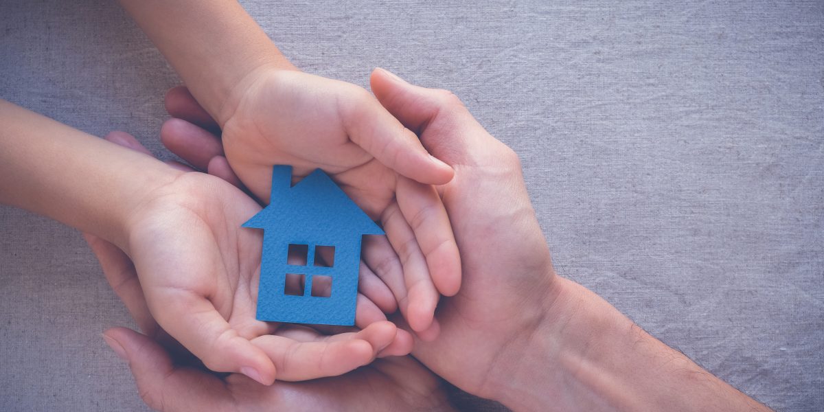 Deux pairs de mains superposés soutenant une maison miniature