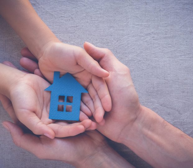 Deux pairs de mains superposés soutenant une maison miniature